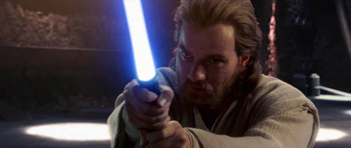 A man aims a lightsaber at something off screen
