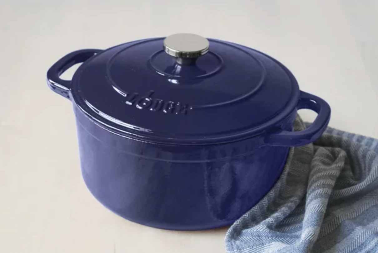 the blue dutch oven on a counter with a blue striped dishcloth