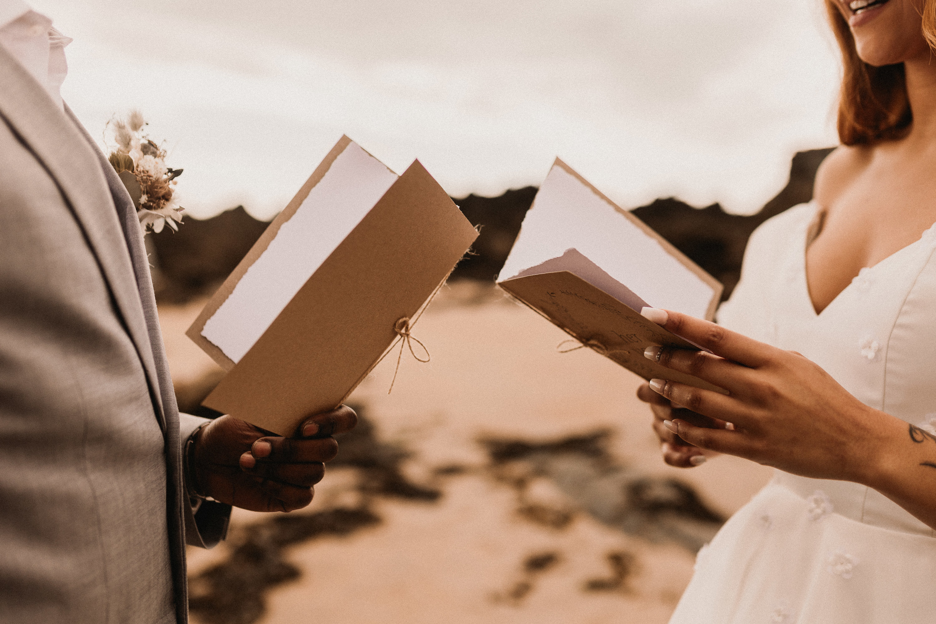 couple reading each other vows on the beach