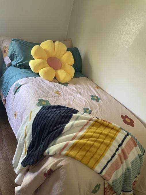 Reviewer&#x27;s yellow and pink flower pillow is shown on a bed