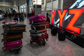 Airplane baggage stacked in front of YYZ sign at Pearson