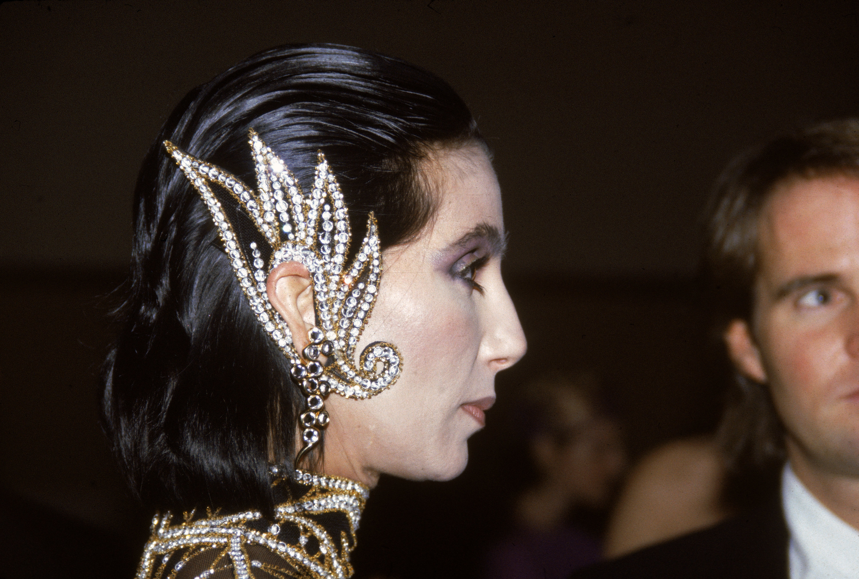 Side profile shot of Cher wearing the ear cuffs, which look like wings and are studded with glittering jewels
