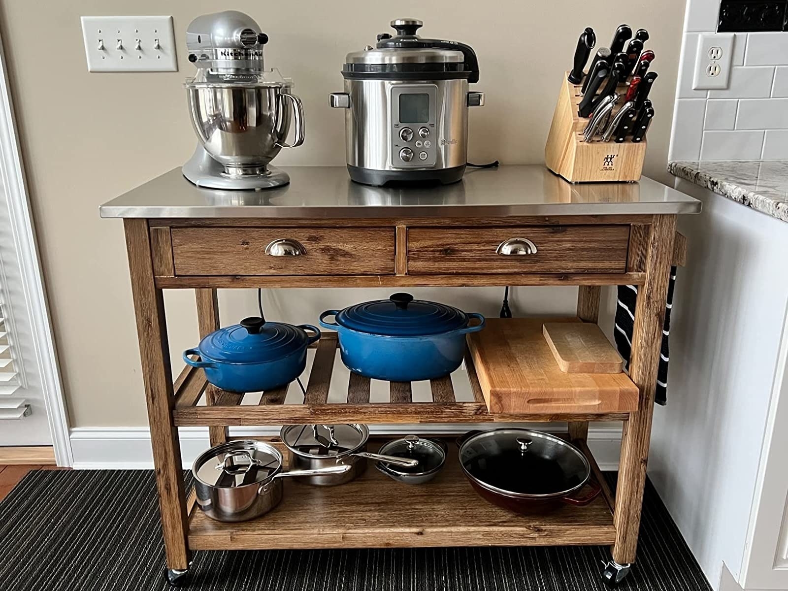 A reviewer&#x27;s photo of the rolling kitchen cart displaying pots and pans