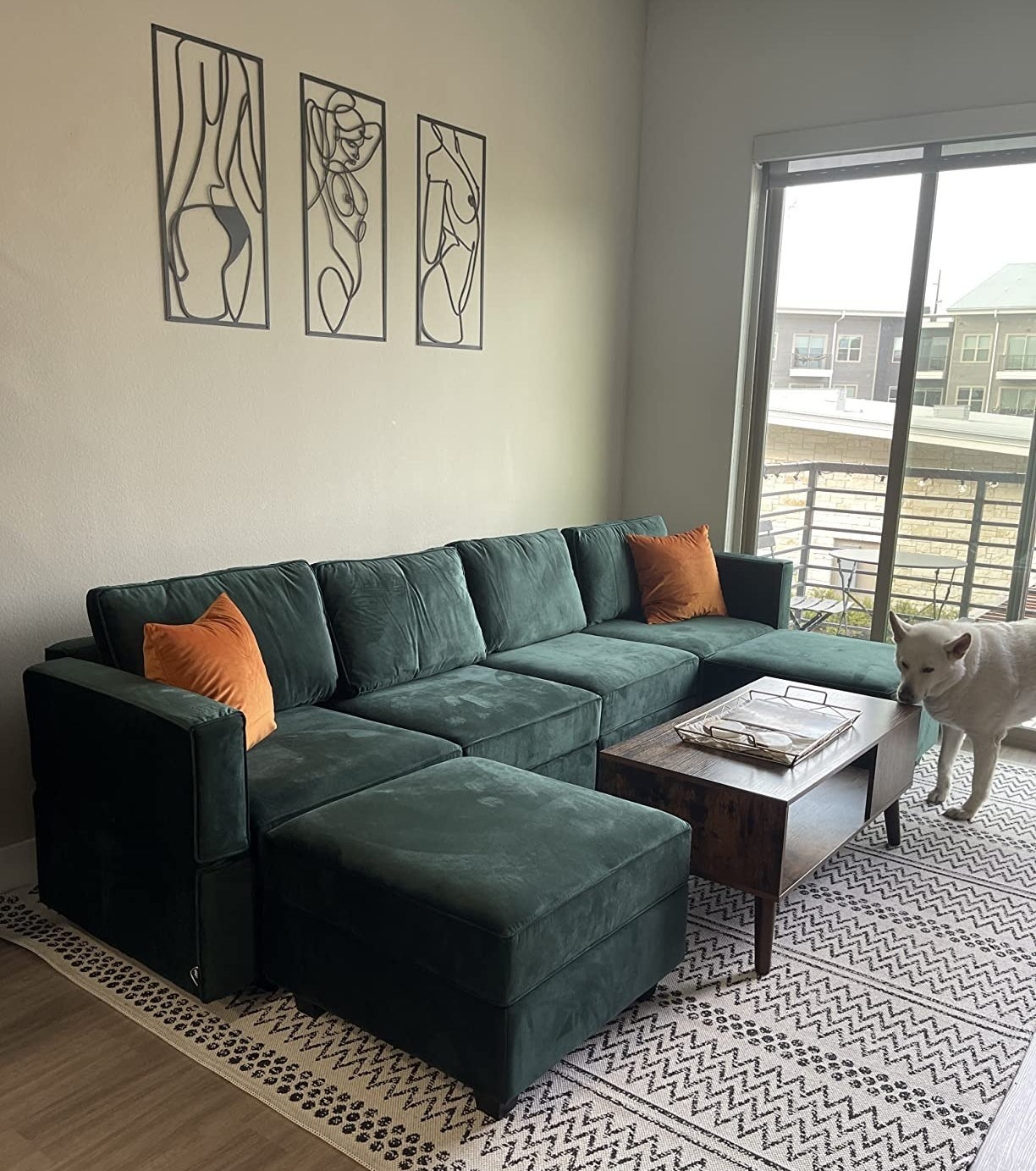 a reviewer photo of the green couch with a white dog next to it