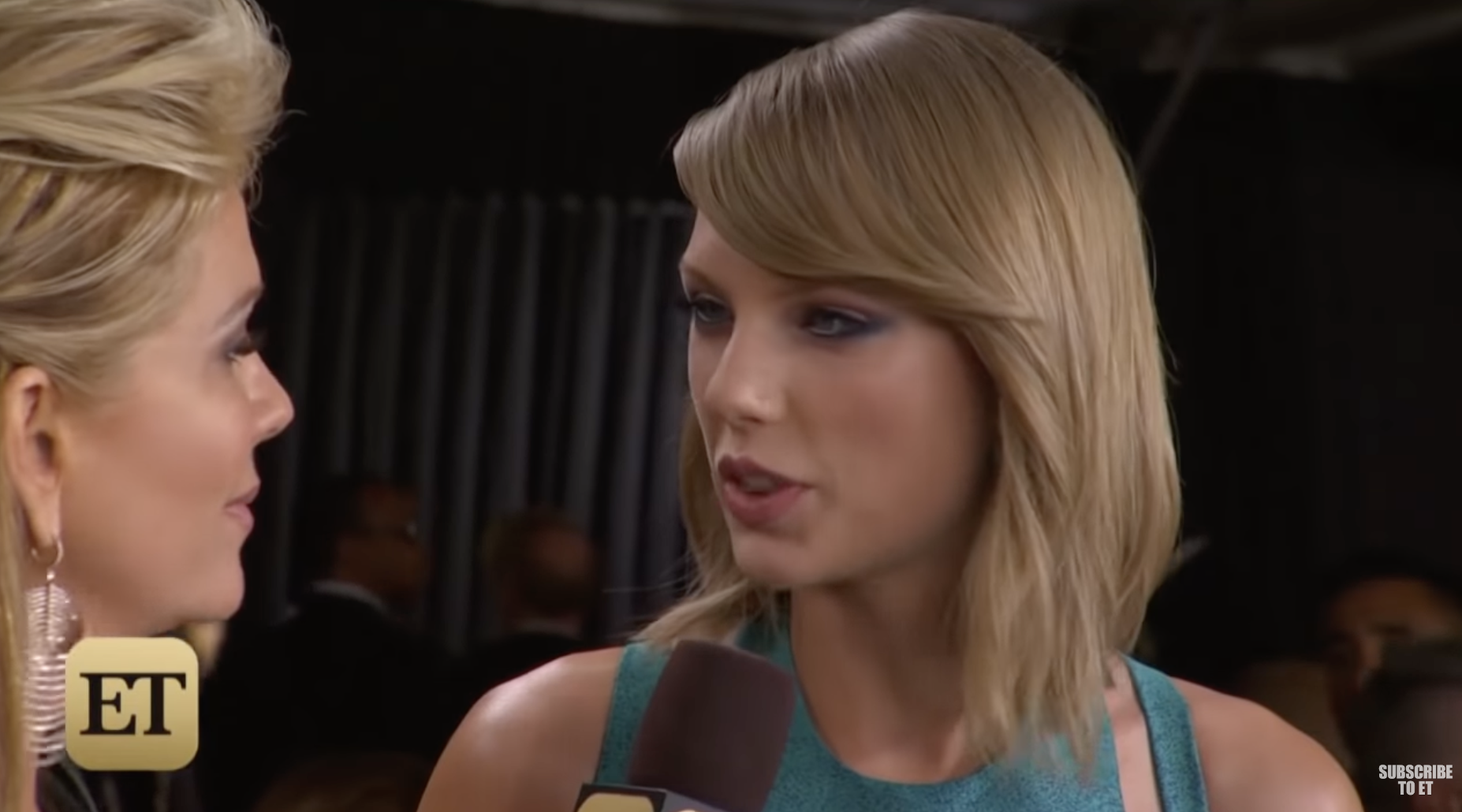 Taylor Swift is on the red carpet, being interviewed by a blonde lady who is holding a microphone up