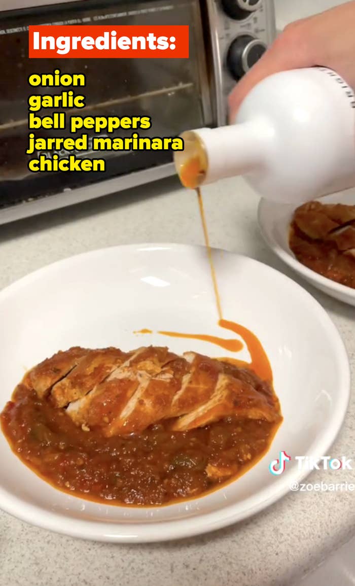 Pouring olive oil onto plated chicken dish in sauce with onion, garlic, bell peppers, marinara