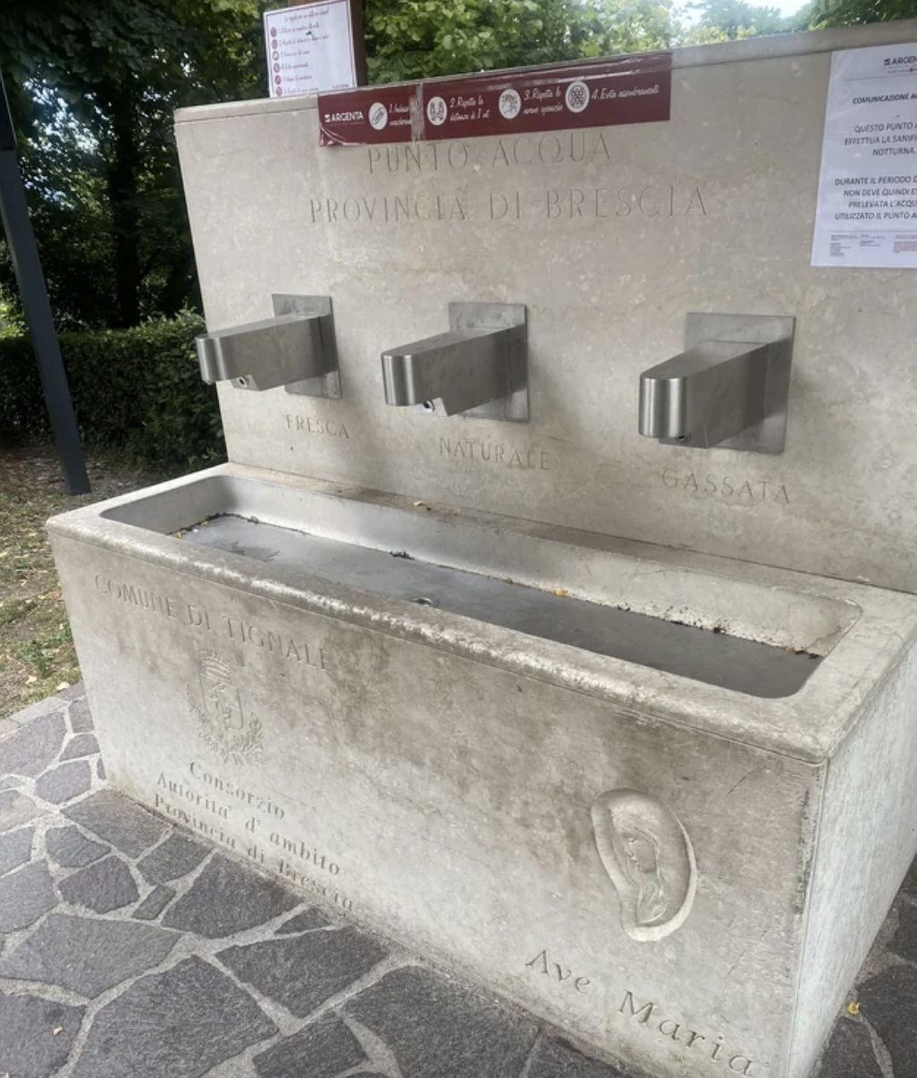 A public water fountain has spouts labeled natural, fresh, and sparkling