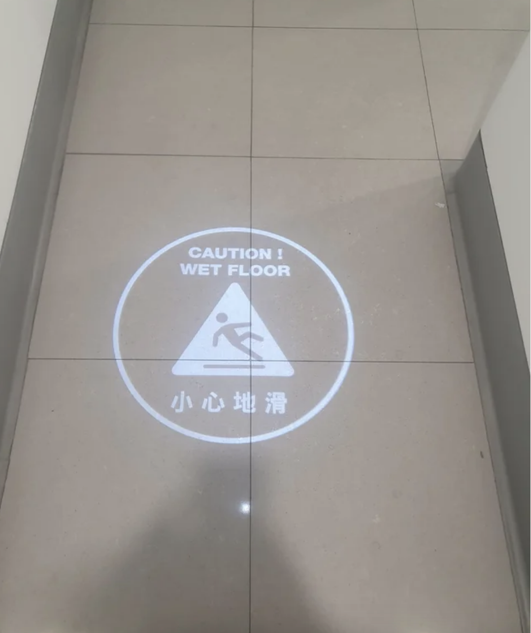 A light shines on the floor that says wet floor