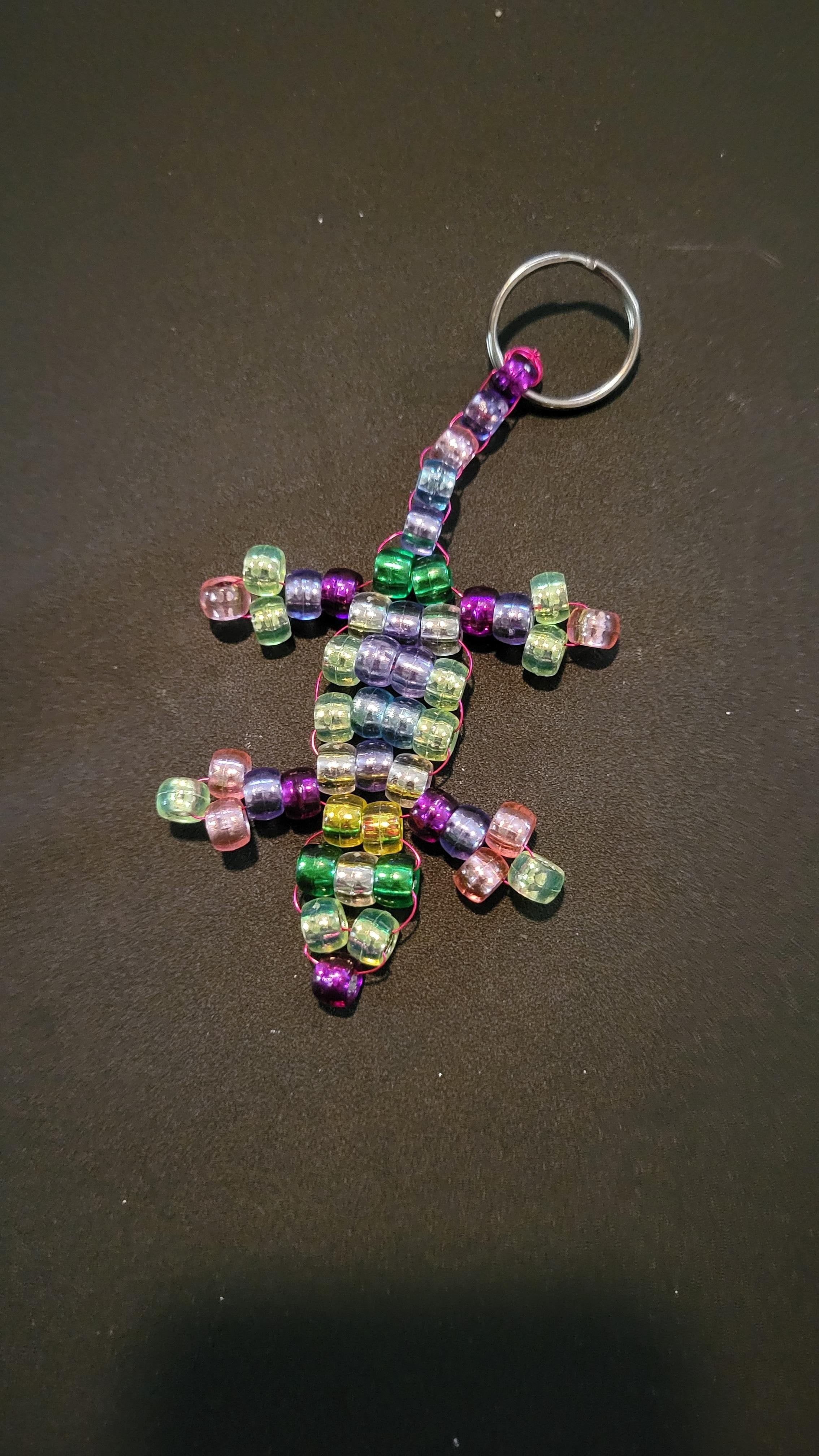 A plastic beaded keychain in the shape of a lizard