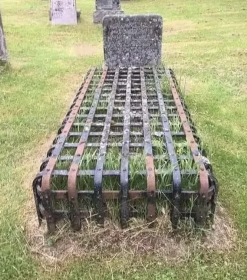 A grave in the ground covered by a metal cage