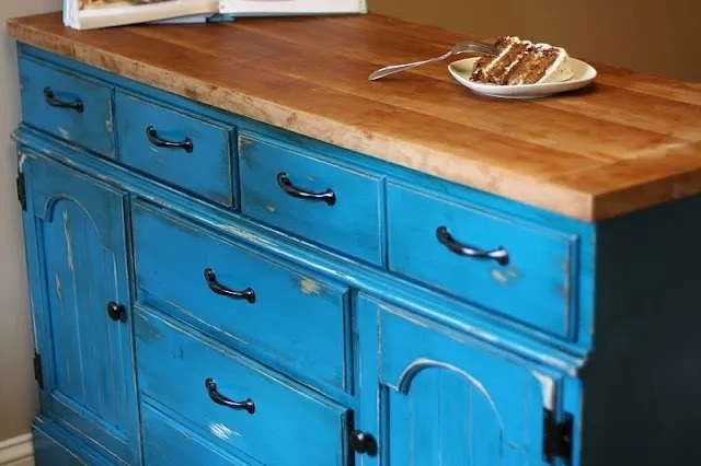 bright blue kitchen island with many drawers and cabinets, and butcher block countertop