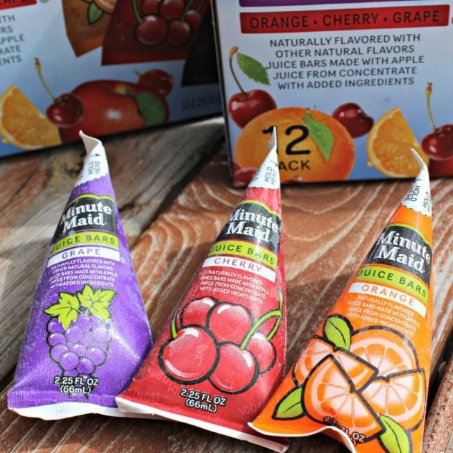 A grape, cherry and orange frozen snack sitting side-by-side