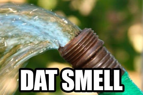 Text reading &quot;dat smell&quot; overlaid over a photo of a hose with running water spraying upward