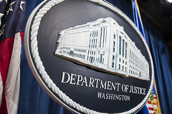 The Department of Justice logo hangs as the backdrop before a press conference
