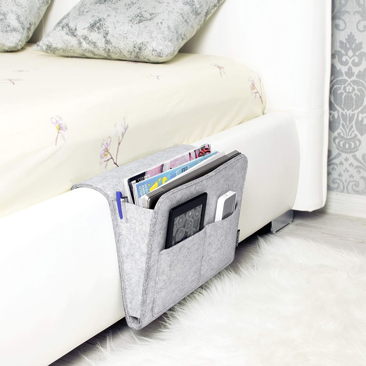 The bedside caddy is tucked into the side of a bed