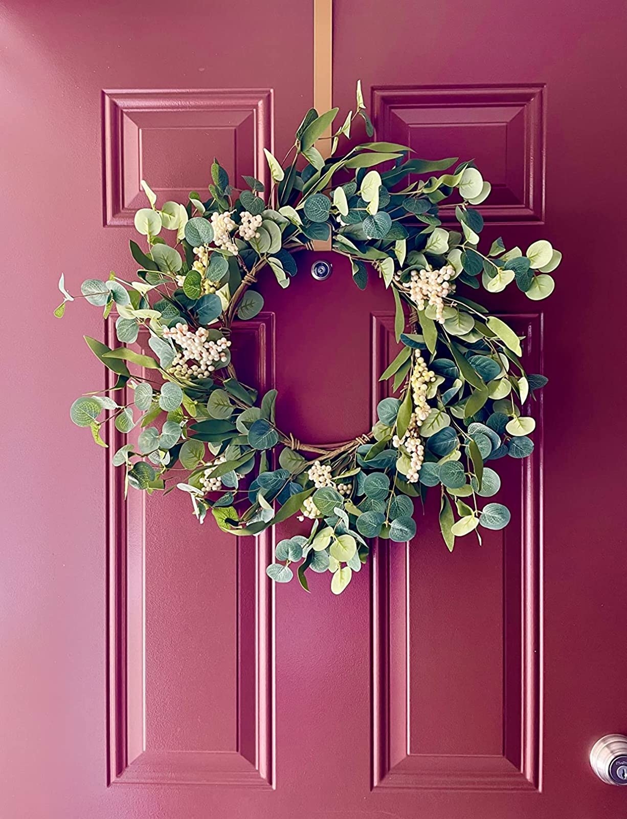 A reviewer&#x27;s photo of the wreath on their maroon front door