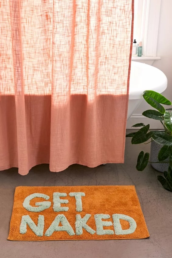 The bath mat in the orange colorway with the &#x27;get naked&#x27; slogan