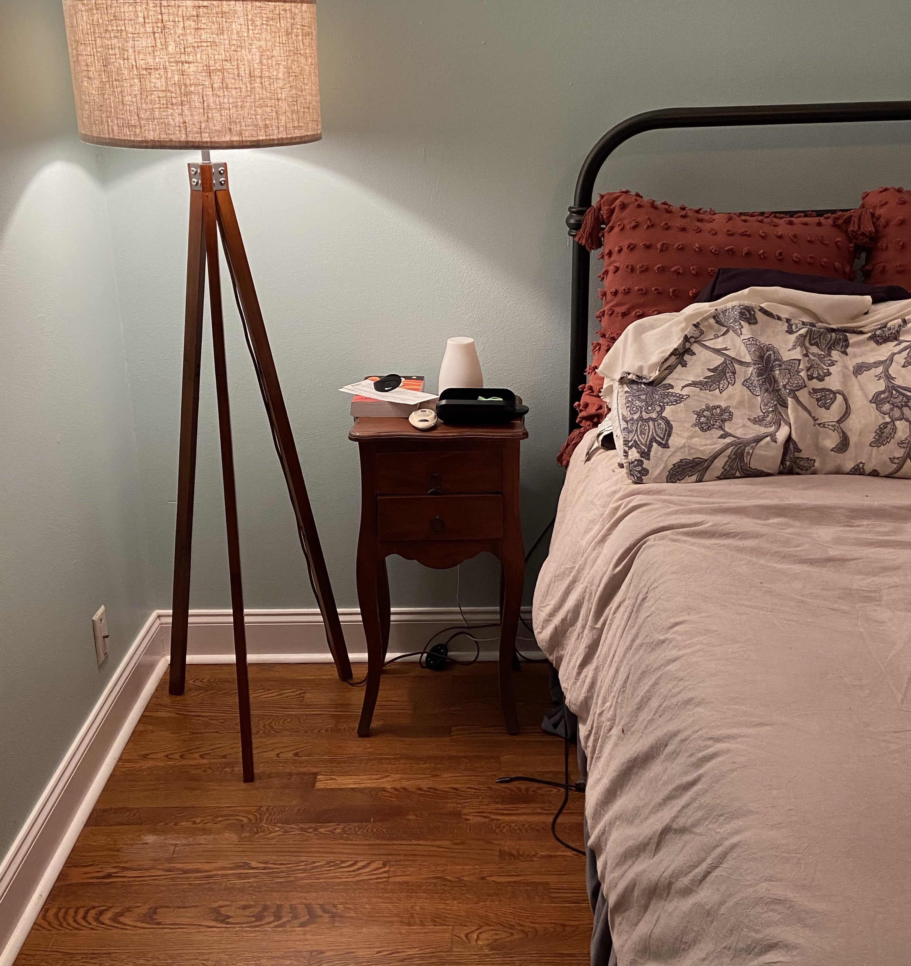 A reviewer photo of the lamp next to a bed
