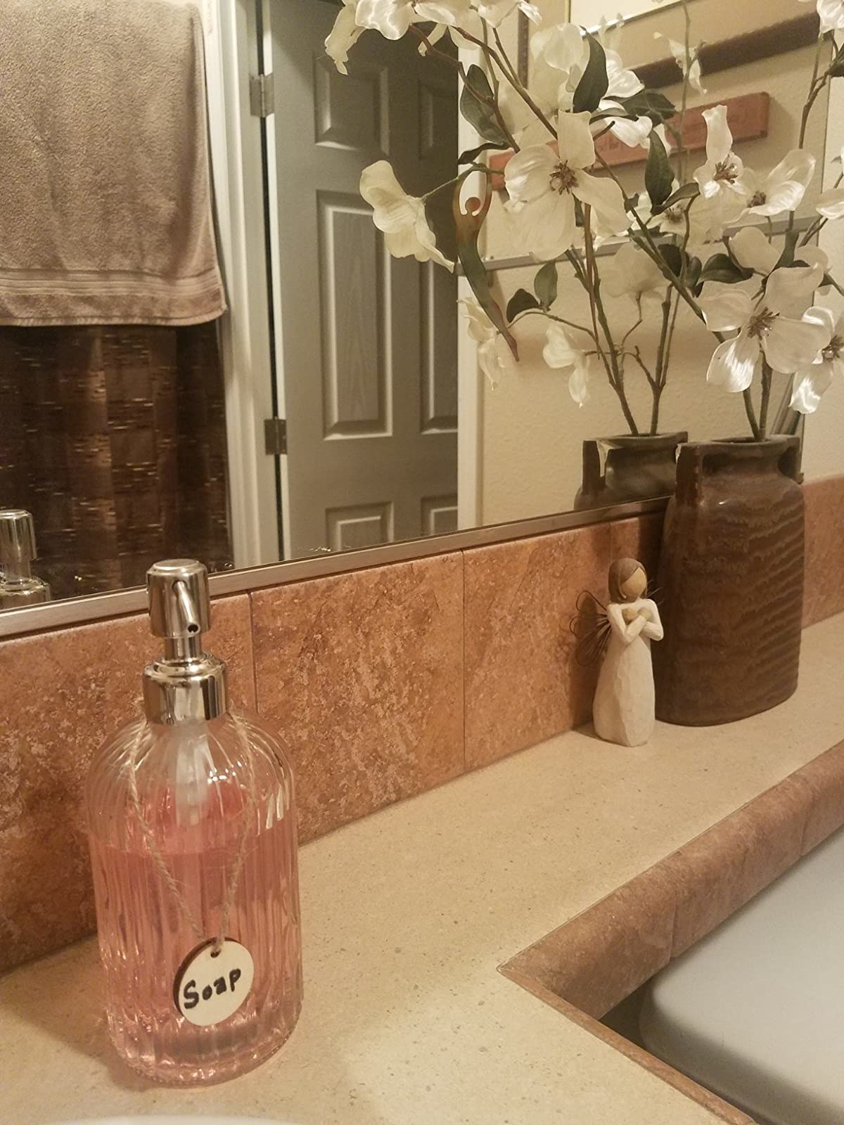 A reviewer&#x27;s photo of the soap dispenser filled with soap and placed on their bathroom sink