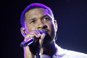 Usher sings into a microphone onstage