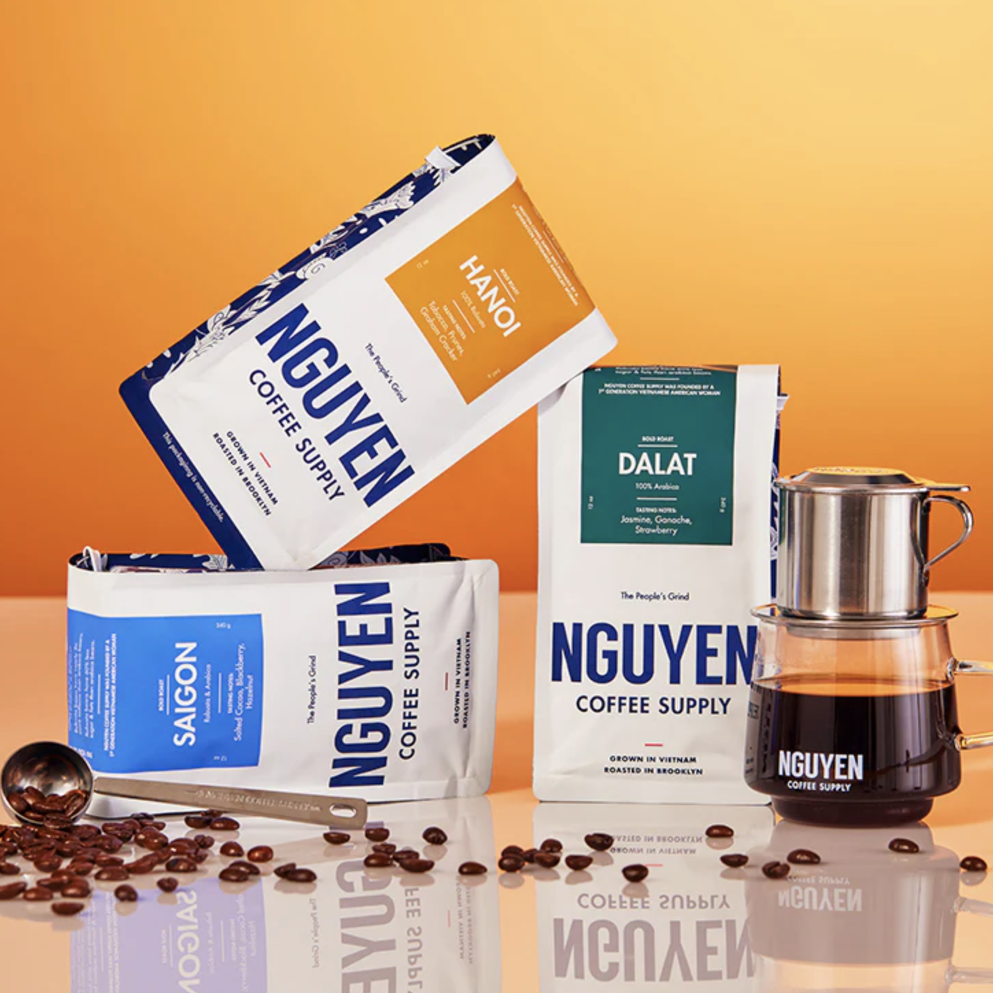 Three bags of coffee stacked on top of each other in front of an orange background.