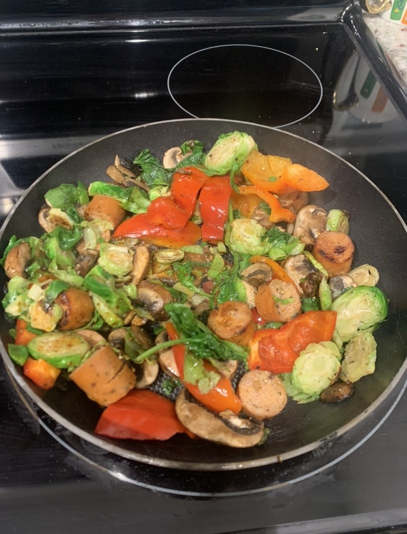 A stove-top pan with a bunch of vegetables and chicken sausage