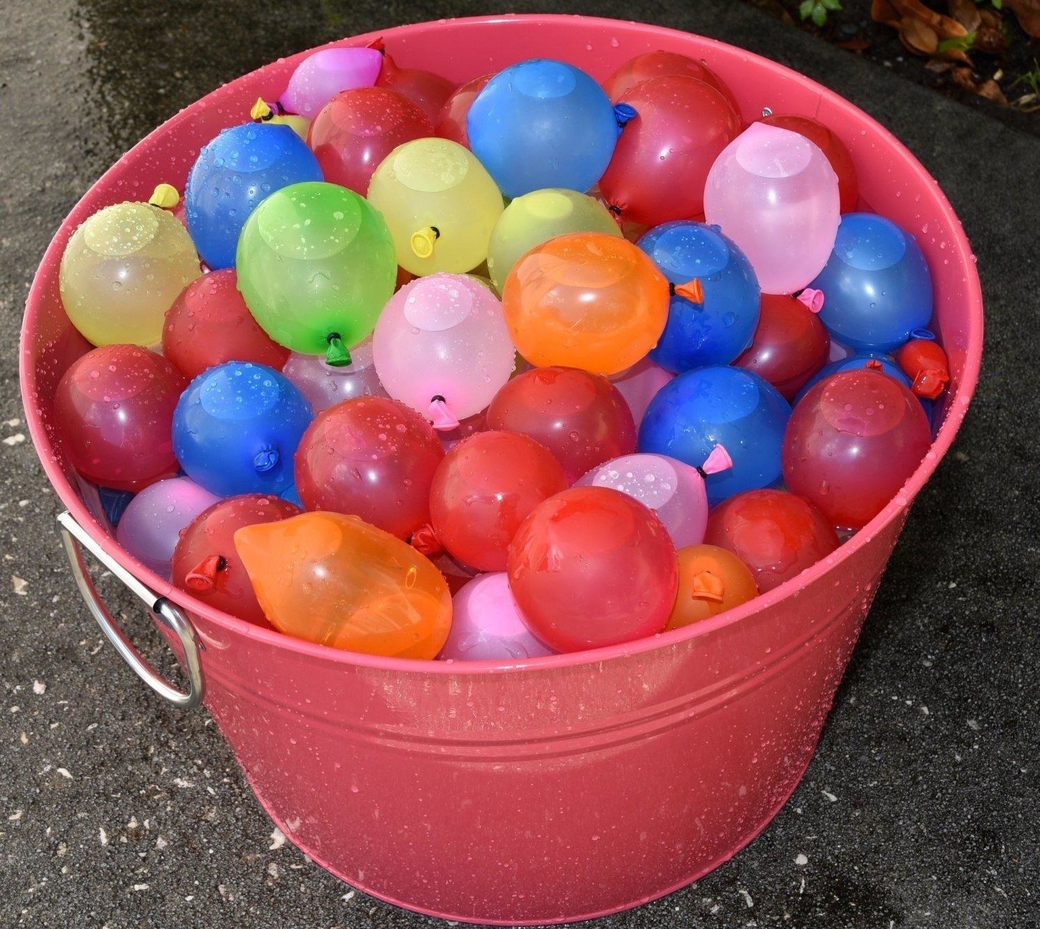 A bucket filled with colorful water balloons that are each filled and tied with water