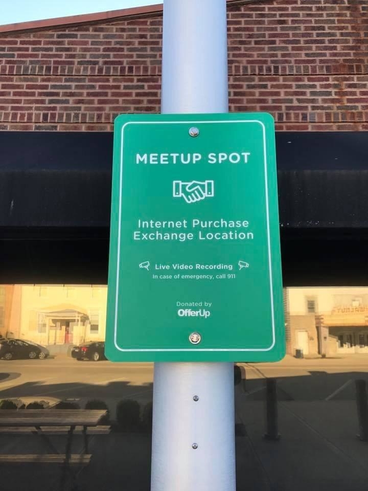 Rectangular sign says &quot;Meetup Spot&quot; with handshake icon and &quot;Internet Purchase Exchange Location&quot; and &quot;Live video recording&quot;