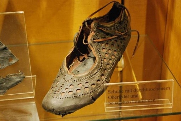A lace-up shoe with a frayed sole and perforations