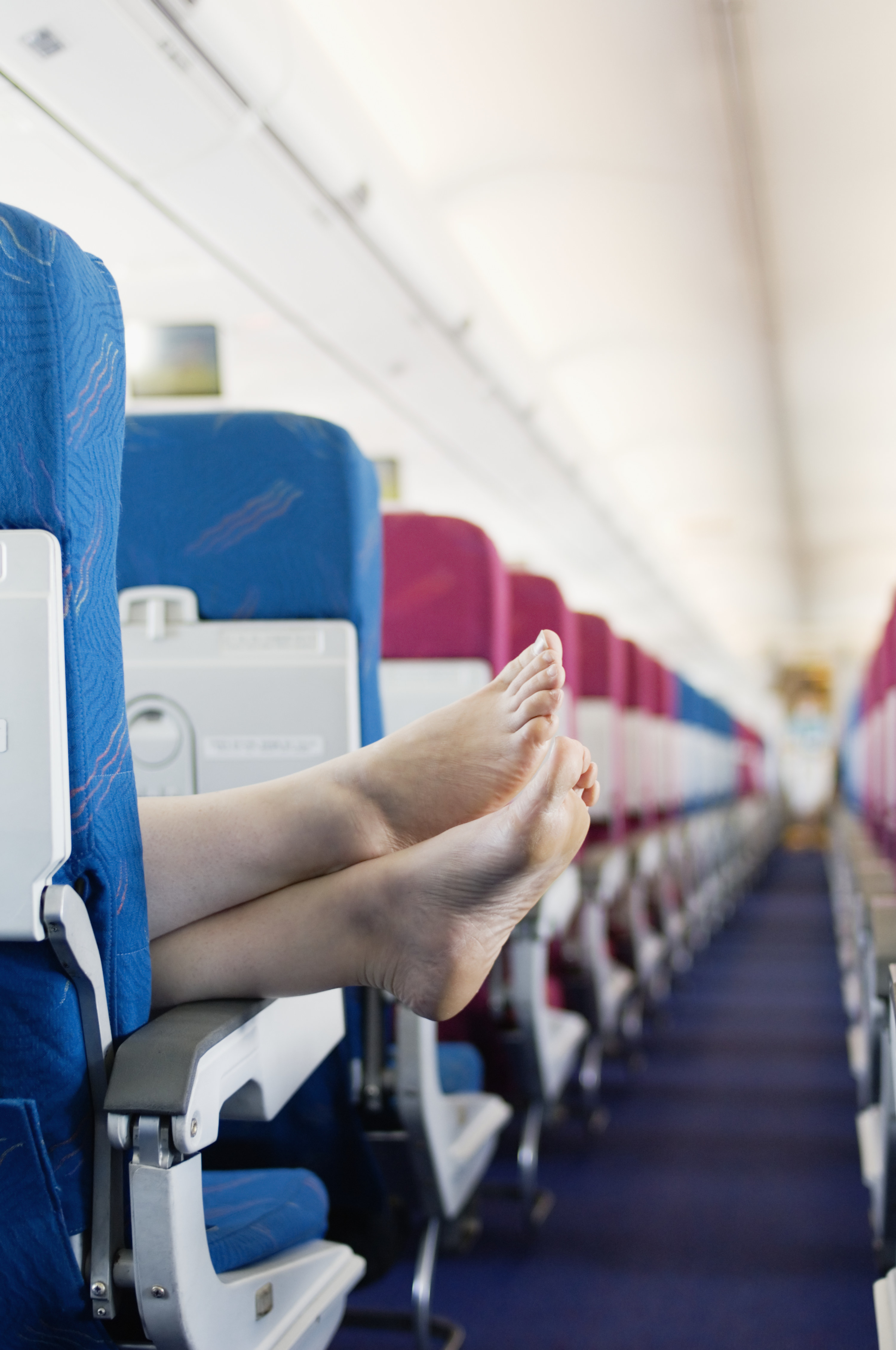 A plane passenger rests their bare feet on a chair