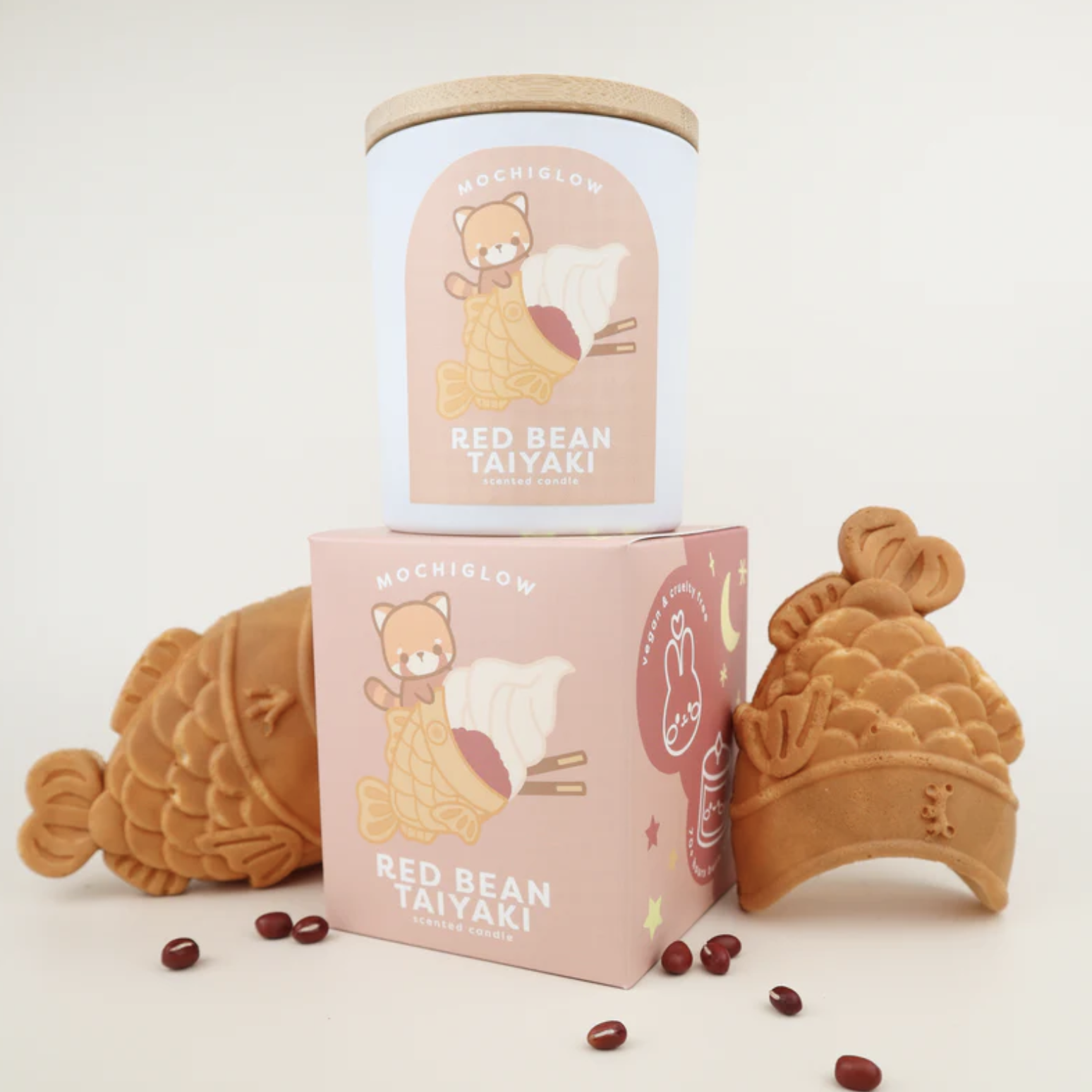 Red Panda and Red Bean Taiyaki themed candle surrounded by taiyaki fish and red beans.