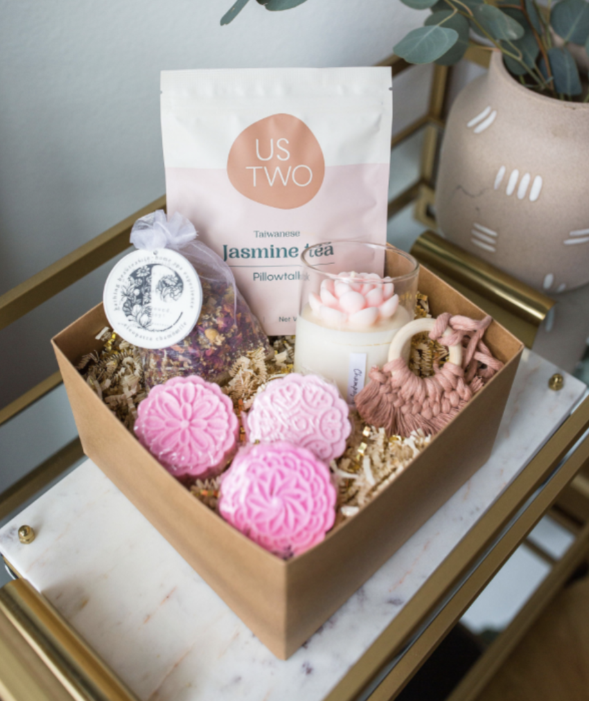Box with pink themed bath bombs, teas, candles, and more