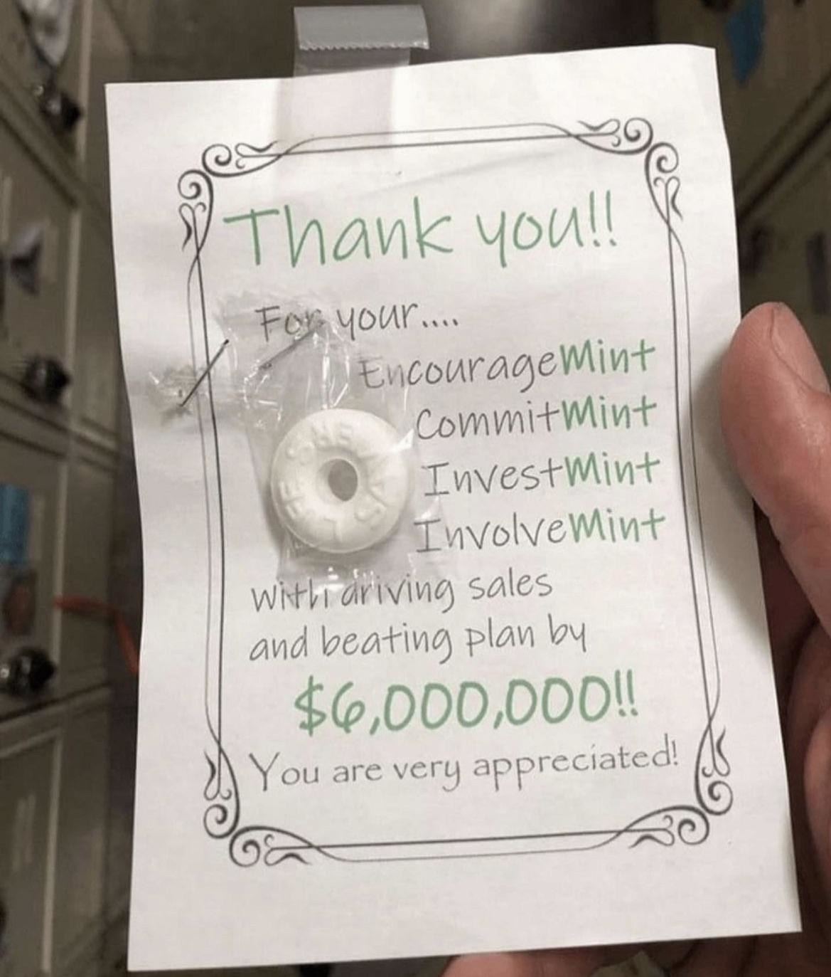 An employee holds a sign thanking them for their work with a single mint stapled on