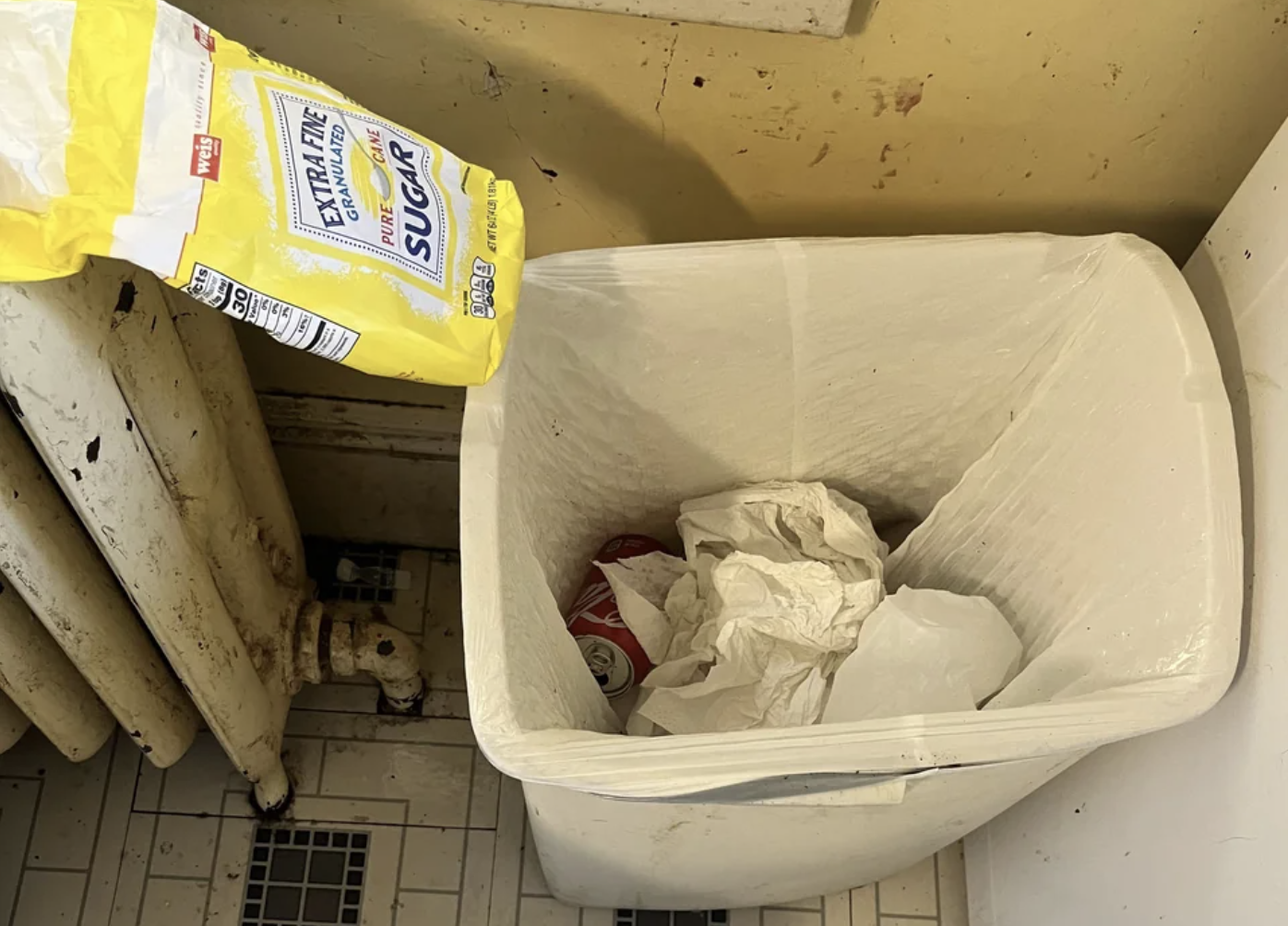 A piece of trash that was placed next to trash can instead of inside of it