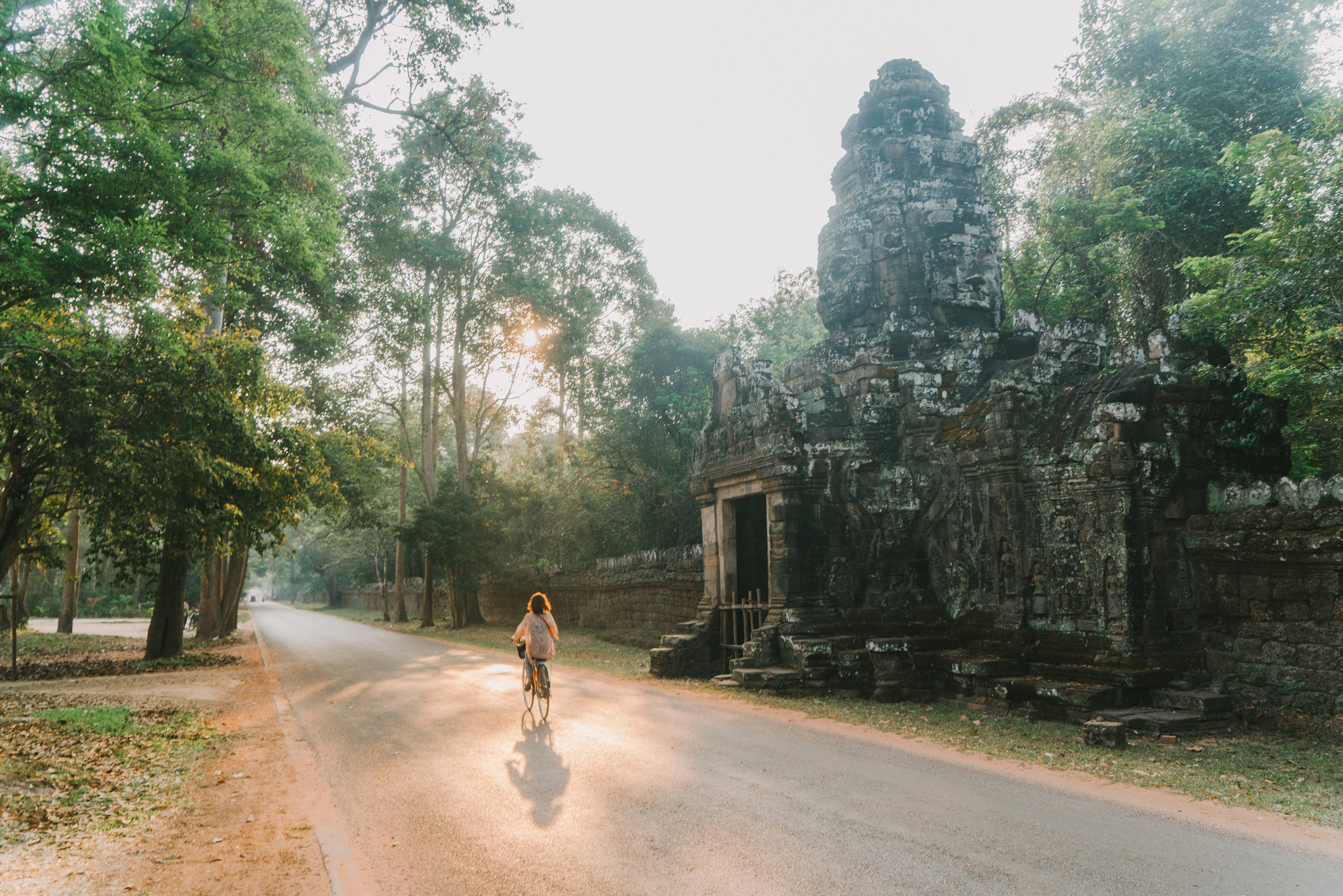 A woman riding a bike by a temple.