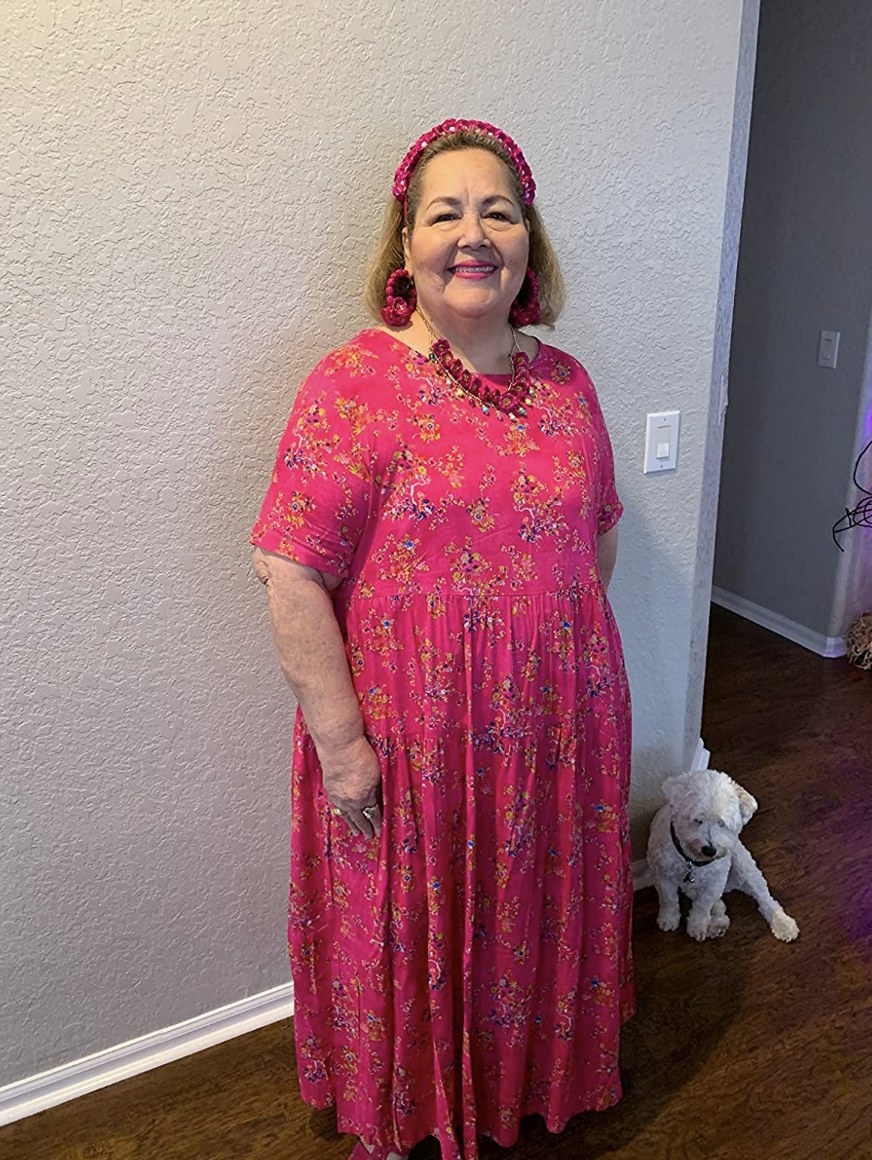 A customer wearing the dress in hot pink with floral details