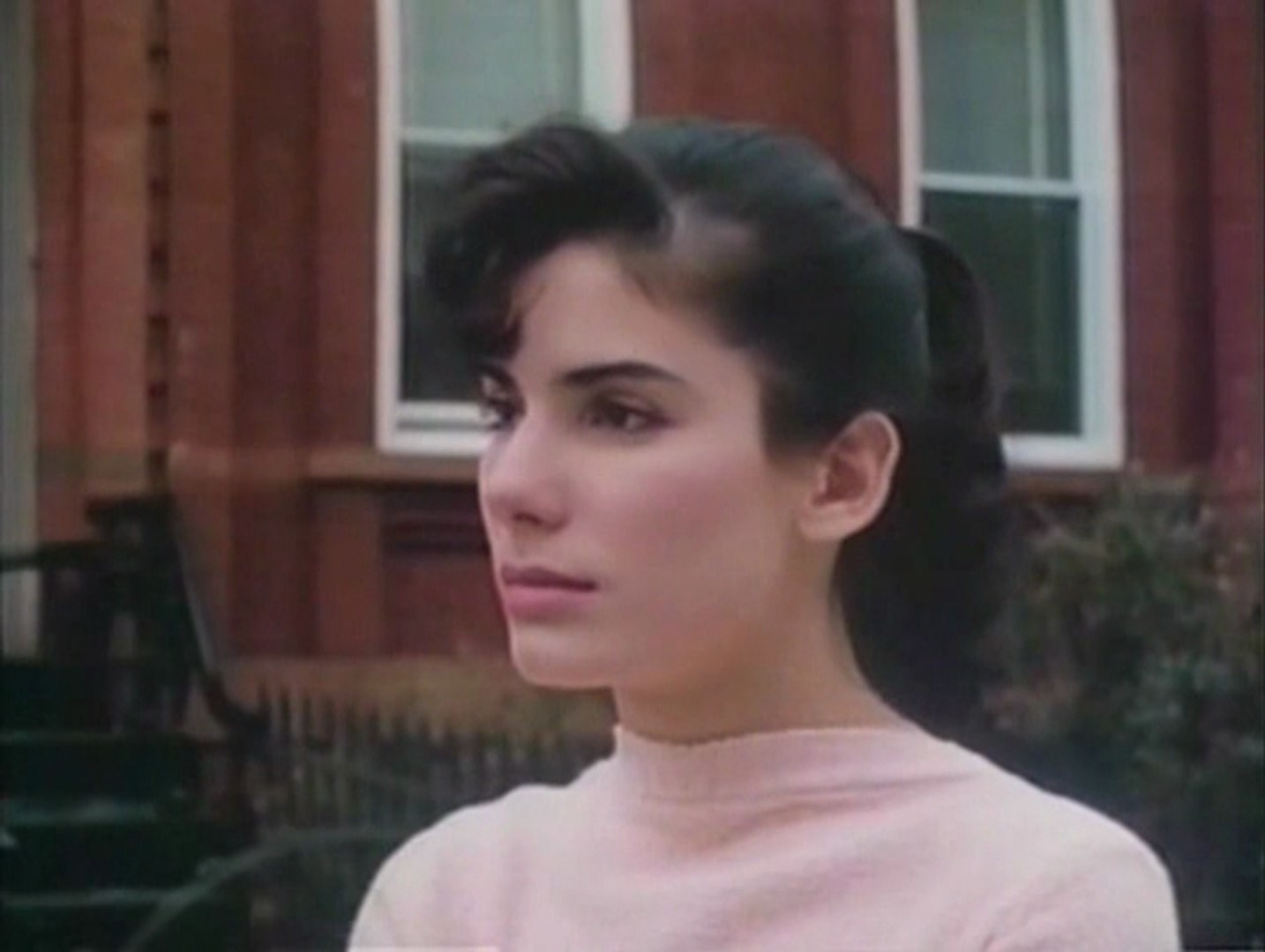 A young Sandra Bullock has a 1950s ponytail hairstyle and looks emotionally into the distance