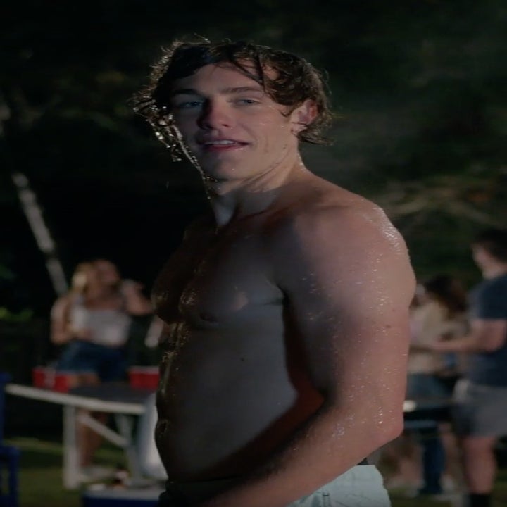 A teen boy emerges from a pool shirtless.