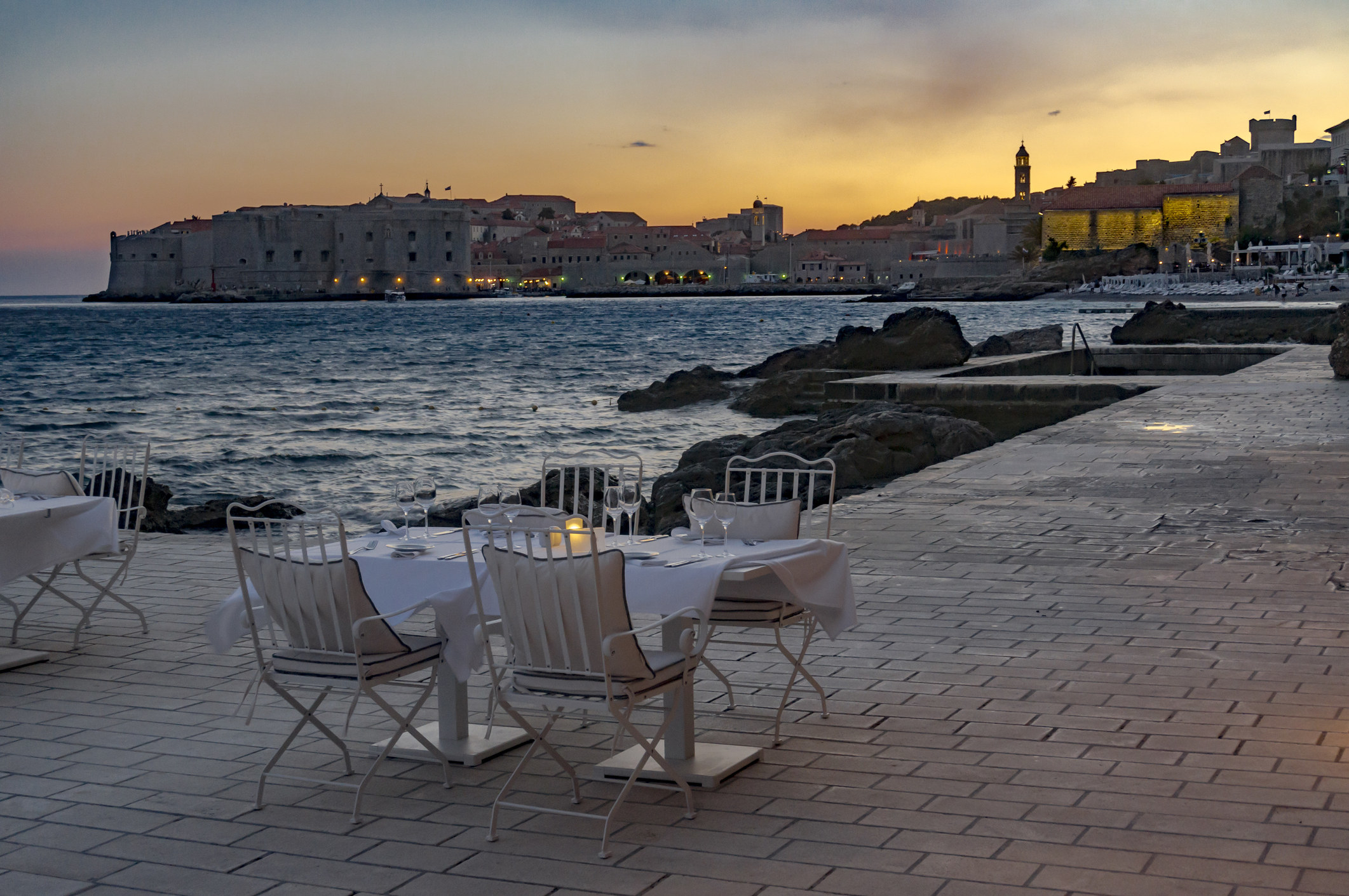 A table set up for sunset dinner by water.