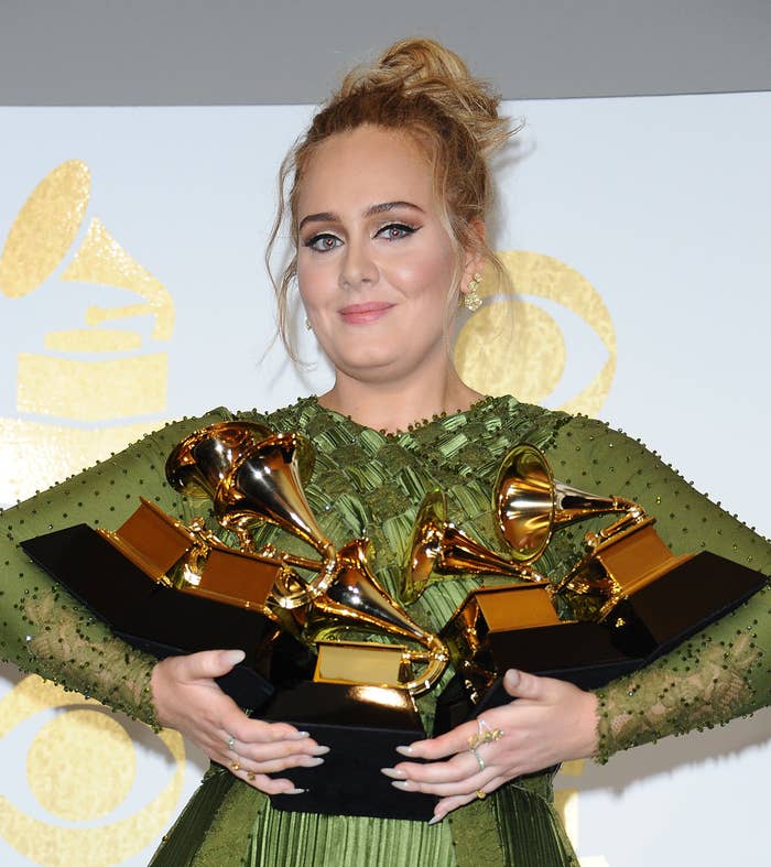 Adele holding five Grammys in her arms