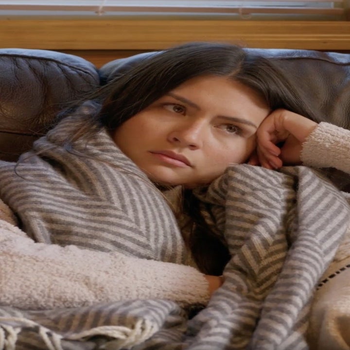 A woman looks frustrated as she sits on a couch.