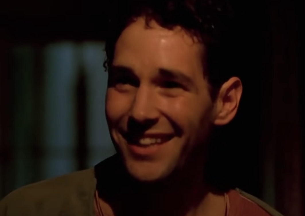 Paul Rudd looks scared and sweaty, smiling in a dark corridor