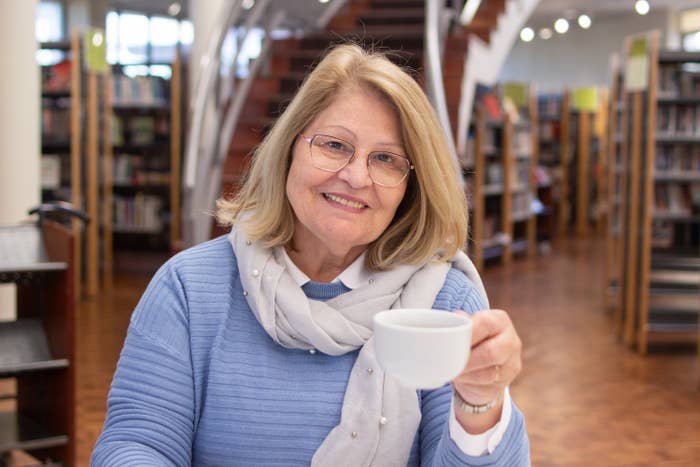A person holding a cup as they sit in a bookstore