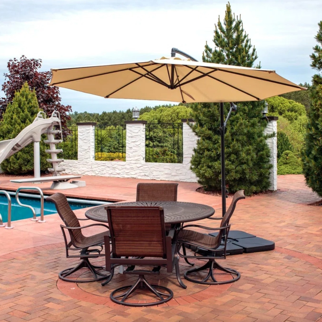 the tan umbrella casting shade over a brown outdoor table on a pool deck