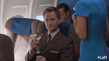 Barney from How I Met Your Mother drinking a martini on a flight