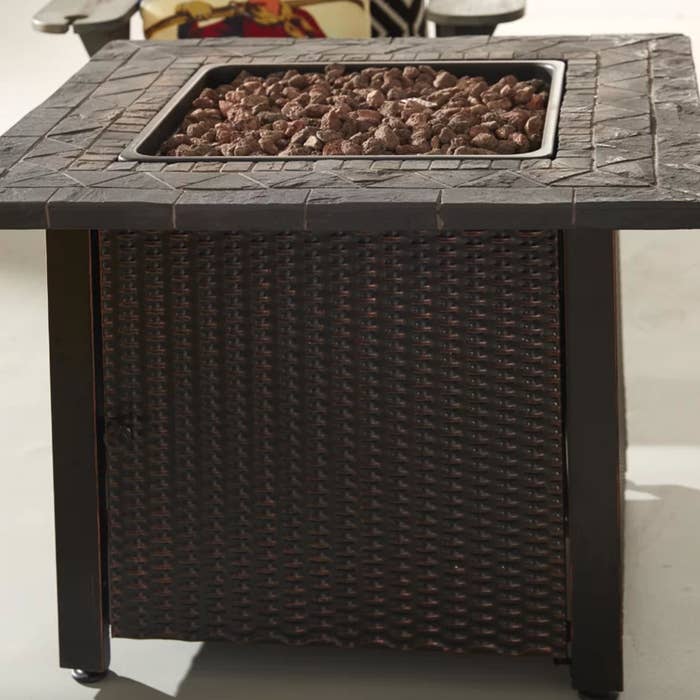 the brown and black fire pit table with a lava rock center