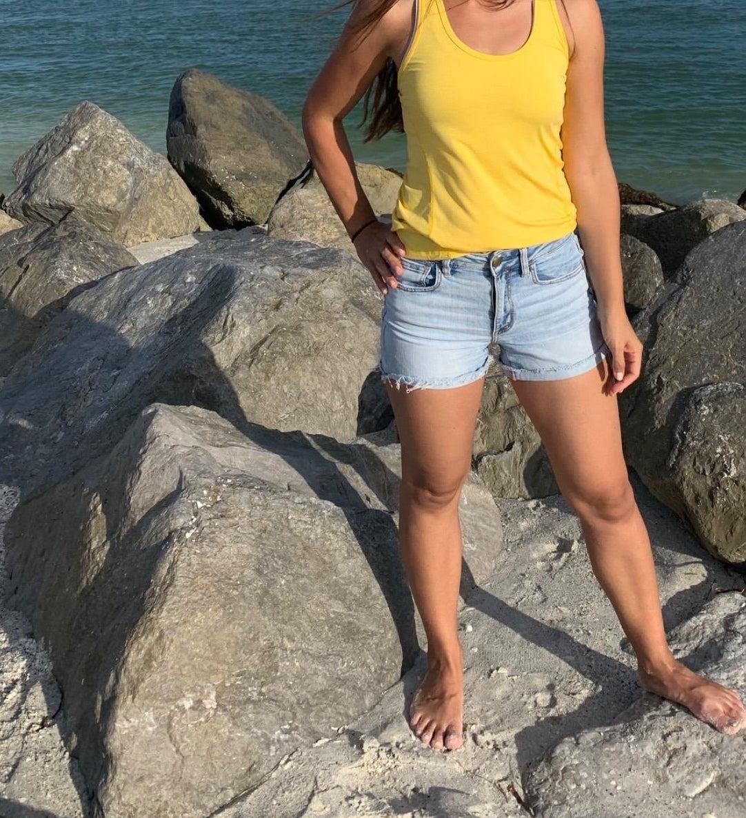 Reviewer standing on beach rocks in yellow tank