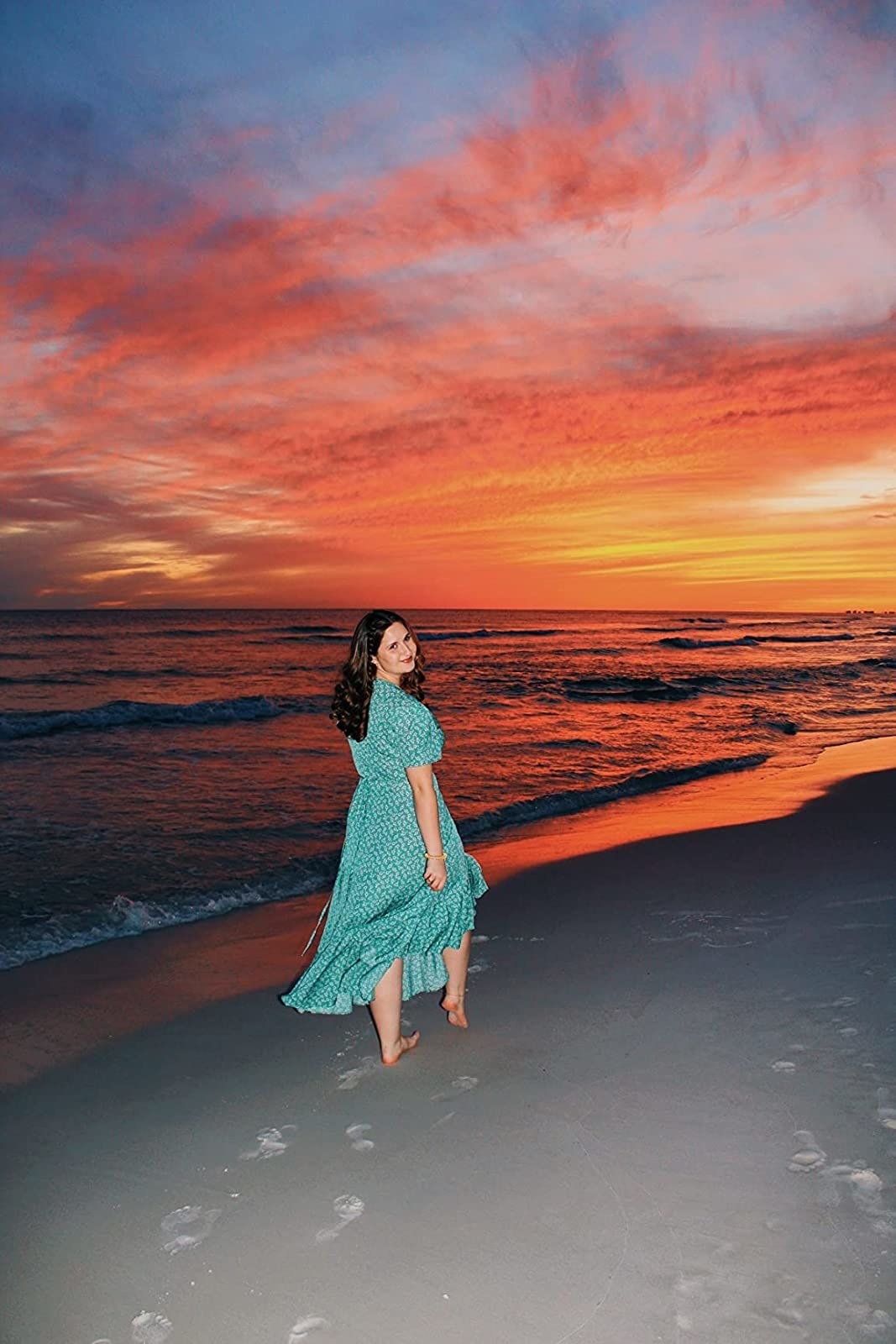 Reviewer on beach at sunset in teal polka-dot dress