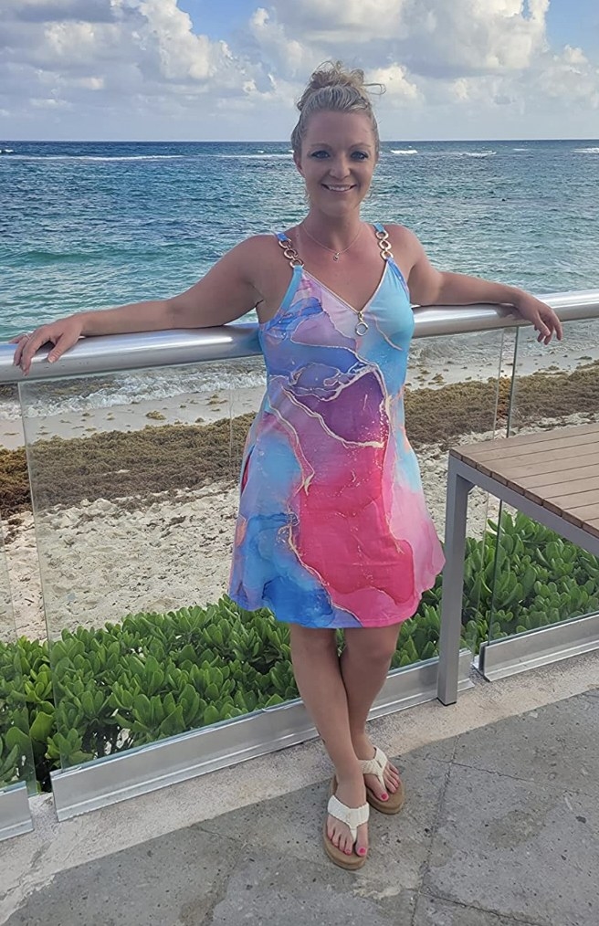 A reviewer wearing the dress in a pink and blue water color pattern
