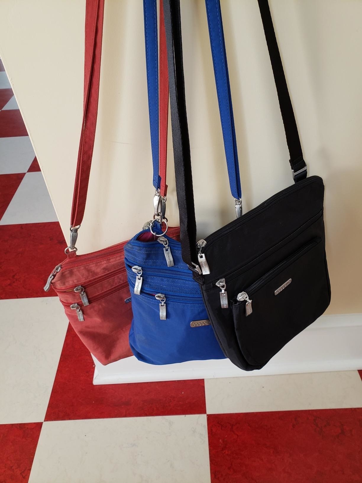Reviewer&#x27;s red, blue, and black Baggallini bags hanging from hook